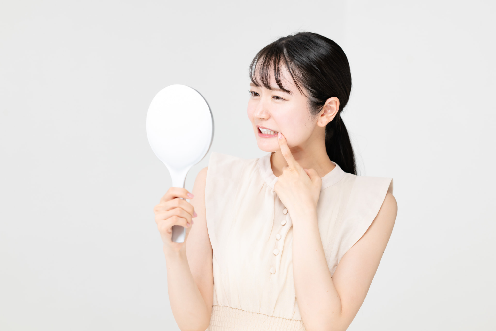 虫歯になりやすい女性が鏡で歯を確認しているイメージ